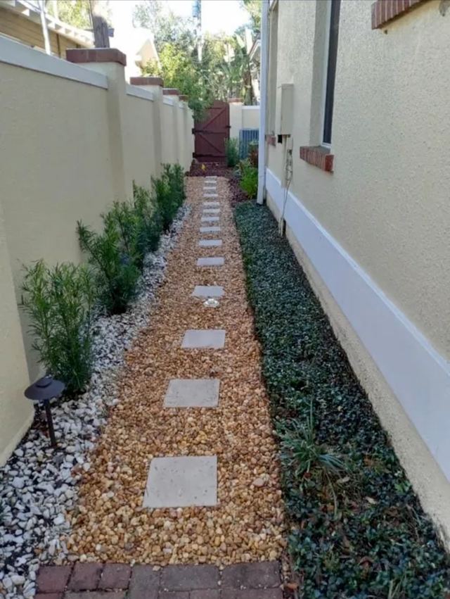 Side yard finished with a stepping-stone path, gravel and shrubs along the wall